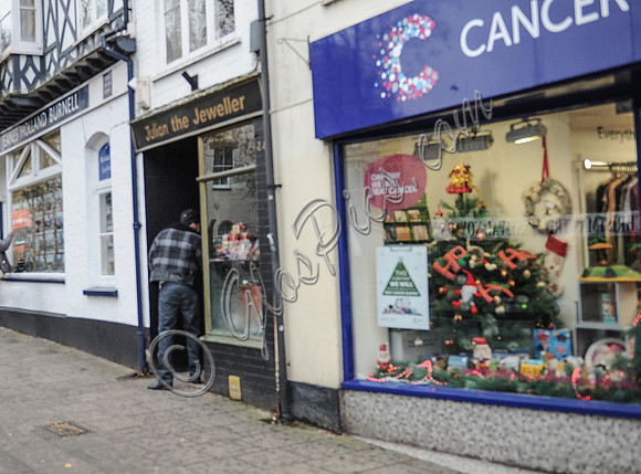 Nicolas Cage wearing plaid jacket and beanie hat emerging alone and backwards from "Julian the Jewellers", in Glastonbury, Somerset.