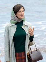 Close up of Rachel Weisz on beach carrying handbag, wearing 60's style pale green raincoat and headscarf