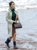 Rachel Weisz on beach carrying handbag, wearing 60's style pale green raincoat, headscarf and blue short wellington boots