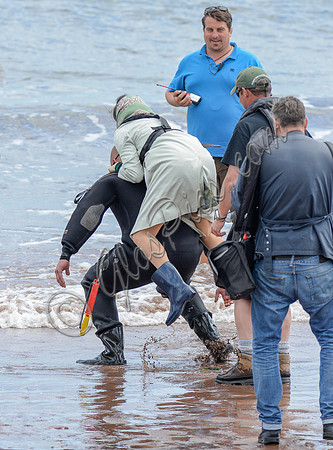 Rachel Weisz being piggy backed to  landing craft, wearing mackintosh, scarf and wellington boots