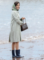 Rachel Weisz on beach carrying handbag, wearing 60's style pale green raincoat, headscarf and blue short wellington boots