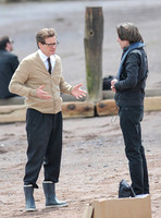 Colin Firth on Teignmouth beach, hands gesticulating, wearing beige cardigan talking to director James Marsh