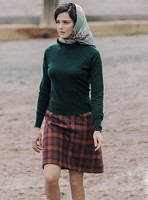 Rachel Weisz on beach wearing 60's style headscarf, green turtle neck sweater and red plaid 'A' line skirtand blue short wellington boots