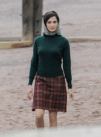 Rachel Weisz on beach wearing 60's style headscarf, green turtle neck sweater and red plaid 'A' line skirt and blue short wellington boots