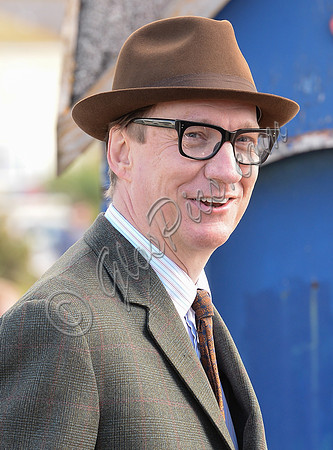 David Thewlis wearing 1960's suit, dark rimmed glasses and trilby hat
