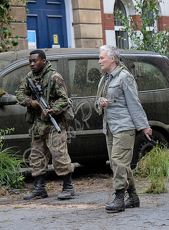 on a dystopian street in fatigues and carrying weapons
