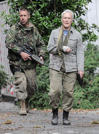 Fisayo Akinade and Glenn Close arm bandaged,  wearing fatigues carrying weapons