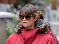 Gemma Arterton close up wearing red padded coat with fur trim and oversized sunglasses