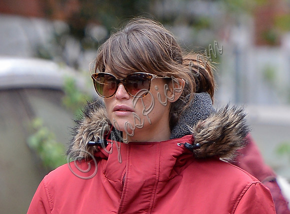 Gemma Arterton close up wearing red padded coat with fur trim and oversized sunglasses