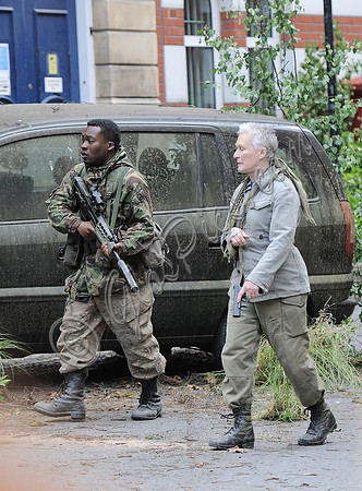 on a dystopian street in fatigues and carrying weapons