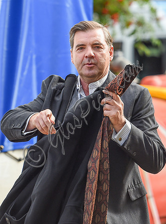 Brendan Coyle carrying a jacket and tie in left hand and gesticulating with his right.