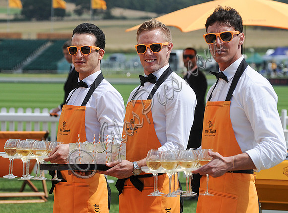 atmosphere - three waiters wearing orange aprons and sunglasses with trays of champagne