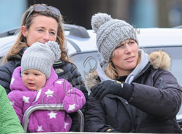 Dolly Maude holds Mia Tindall in pink and white onepiece suit alongside Zara Phillips wearing a matching woolly hat