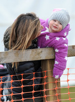 Dolly Maude carries smiling Mia Tindall in pink and white all in one suit and woolly hat