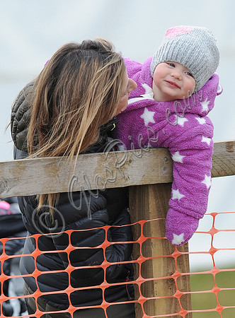 Dolly Maude carries smiling Mia Tindall in pink and white all in one suit and woolly hat