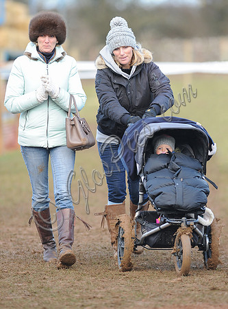 Zara Phillips pushin daughter in buggy wearing matching woolly hats, accompanied by female friend.