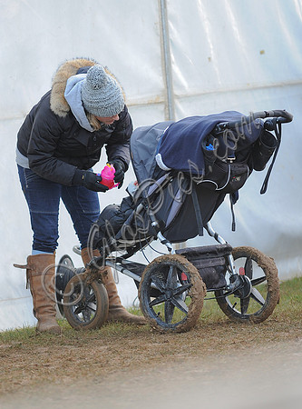 Zara Phillips hands daughter pink drinking cup in buggy.