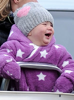 Laughing Mia Tindall in pink and white onepiece with woolly hat.