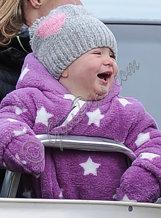 Laughing Mia Tindall in pink and white onepiece with woolly hat.