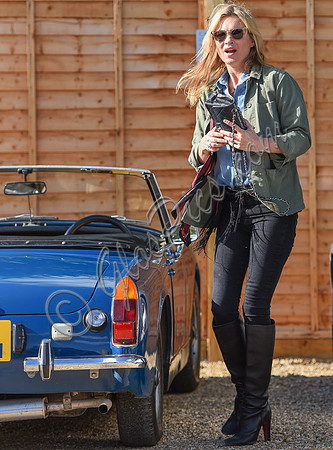 Kate Moss wearing military style jacket, teamed with denim shirt, black skinny jeans, tall Christian Laboutin leather boots carrying a vintage Chanel quilted flap bag.