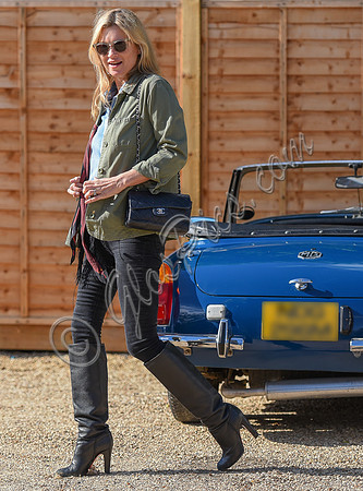 Kate Moss wearing military style jacket, teamed with denim shirt, black skinny jeans, tall Christian Laboutin leather boots carrying a vintage Chanel quilted flap bag.