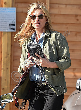 Kate Moss wearing military style jacket, teamed with denim shirt, black skinny jeans, tall Christian Laboutin leather boots carrying a vintage Chanel quilted flap bag.