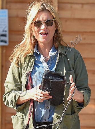 Kate Moss wearing military style jacket, teamed with denim shirt, black skinny jeans, tall Christian Laboutin leather boots carrying a vintage Chanel quilted flap bag.