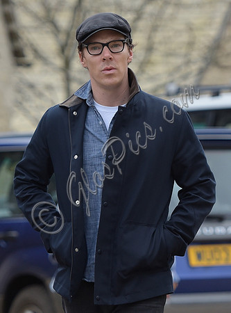 Benedict Cumberbatch wearing denim shirt, flat cap and glasses