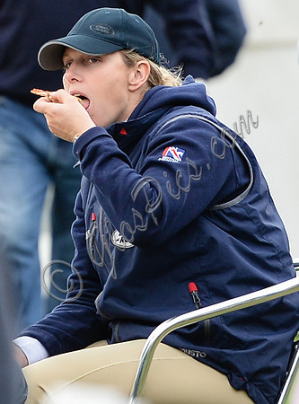 tight side shot of Zara Phillips eating a pizza wearing polo cap and blue MUSTO jacket