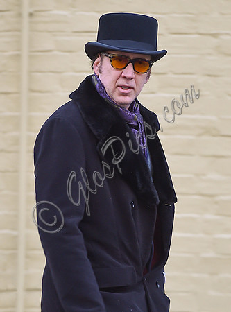 Nicolass Cage waist up wearing top hat and orange sunglasses