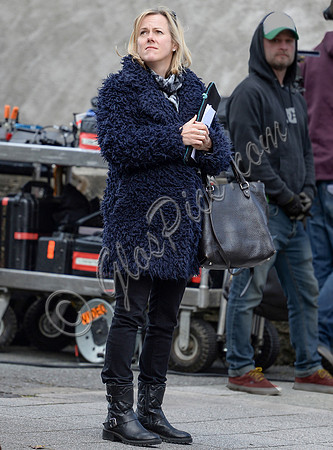 Jojo Moyes wearing navy coat, black tight and black boots on film set