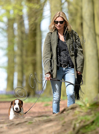 Supermodel Kate Moss wearing military style jacket, skinny jeans and cowboy boots takes a walk with her dog Archie in the woods