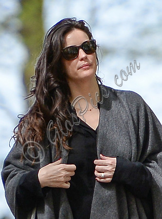 Actress Liv Tyler looking glamourous wearing large sunglasses and poncho - close-up.